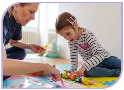 Able Kids Therapy Allied Health Services - Paediatric Occupational Therapy & Speech Therapy. Child sits with therapist on the floor investigating a toys colours and shapes
